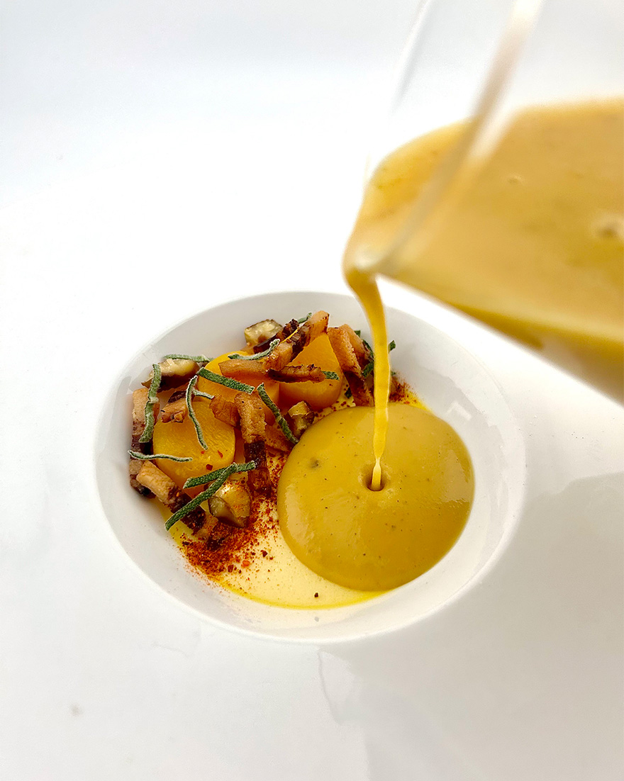 Squash bisque being poured at the table